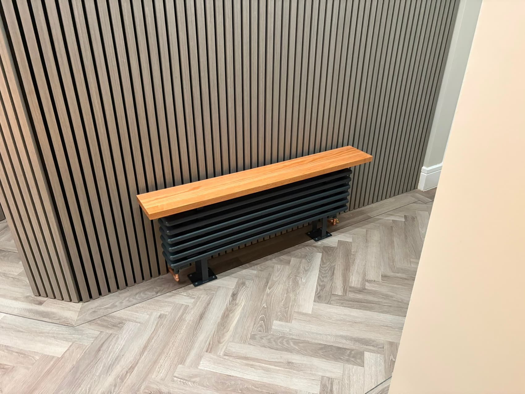 Anthracite column radiator with an oak shelf, angled view