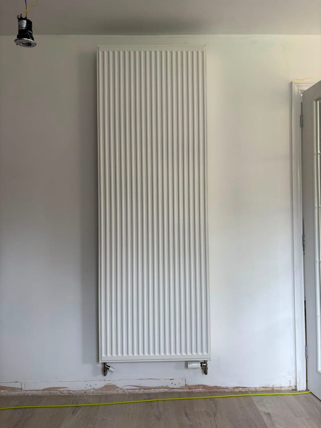 Tall vertical panel radiator fitted in a room