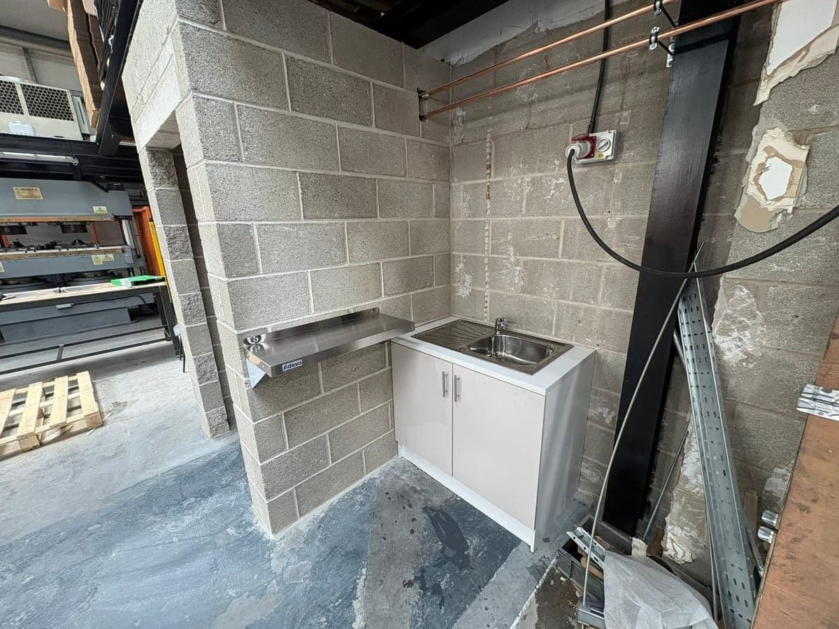 Stainless sink and kitchenette fitted against blockwork