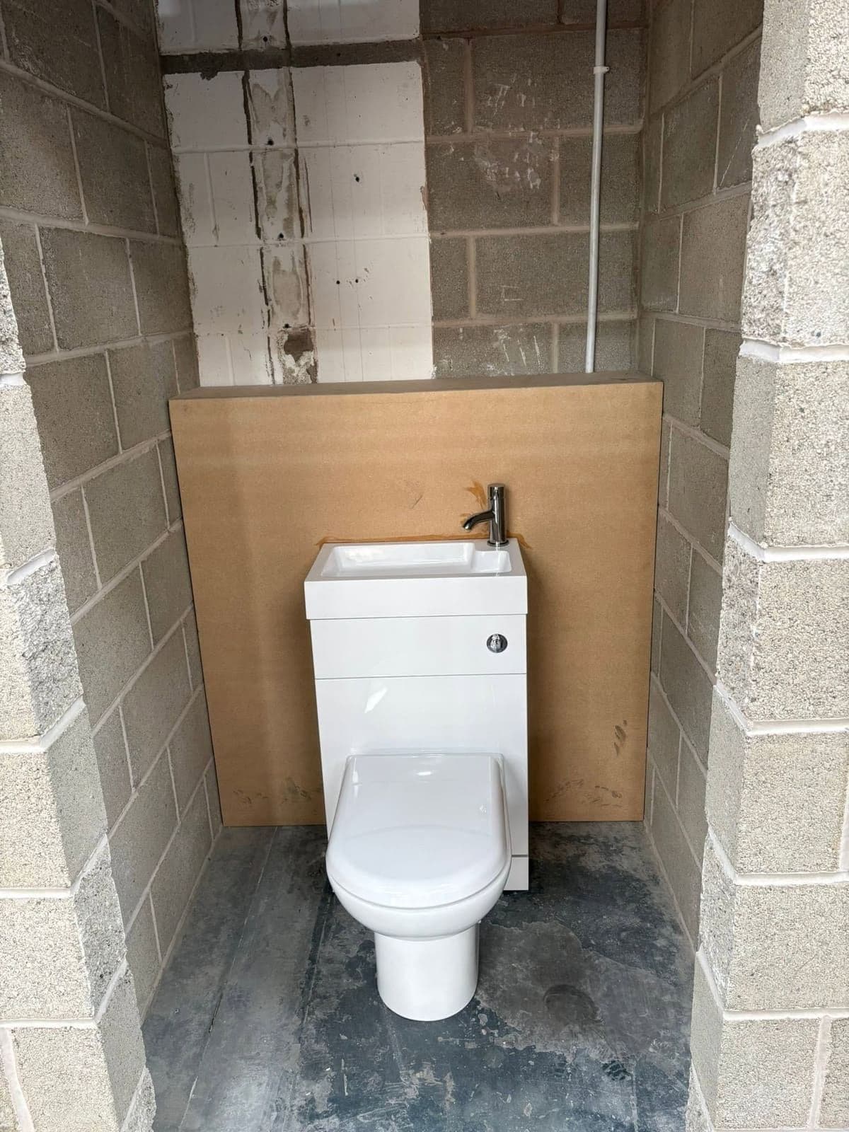 Compact WC and basin unit fitted in a blockwork room
