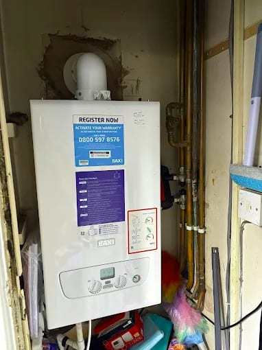 Newly fitted Baxi boiler in a cupboard with the manufacturer's register now warranty sticker still on the front