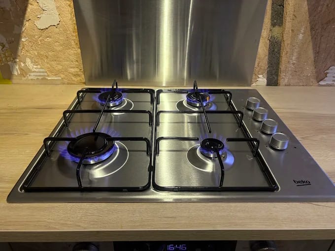 Stainless four-burner gas hob with every burner lit and burning blue